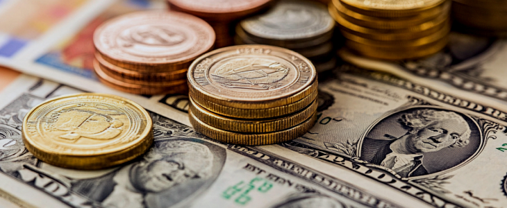 A stack of golden coins and US dollars arranged on top of each other, symbolizing wealth and currency.