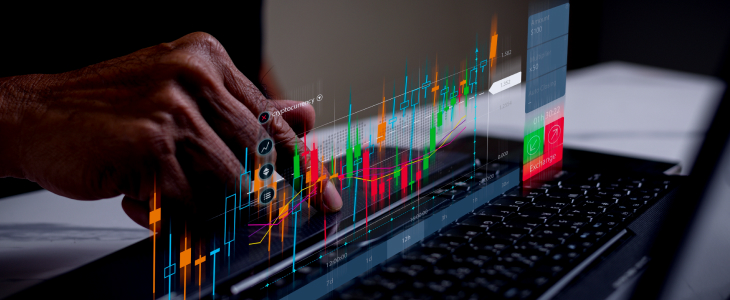 A person focused on a laptop displaying a stock chart, analyzing financial data and trends.
