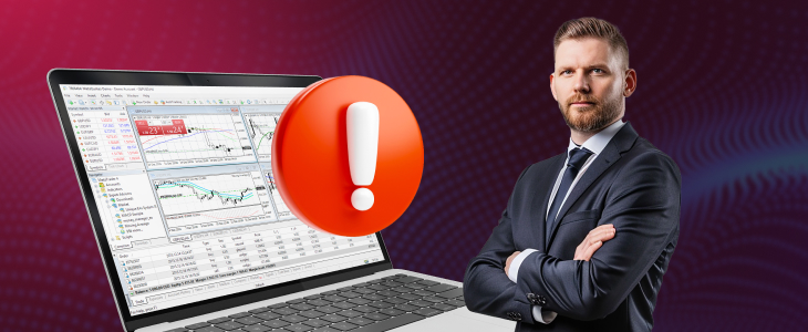 A suited man stands next to a laptop featuring an exclamation mark, suggesting a critical alert or notification.